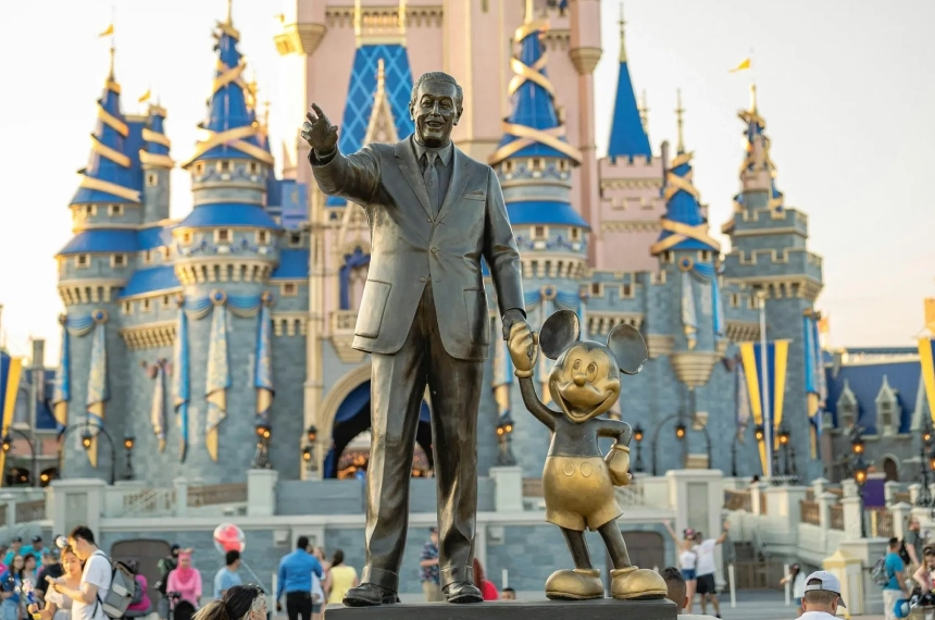 A statue of walt disney and mickey mouse in front of the castle.