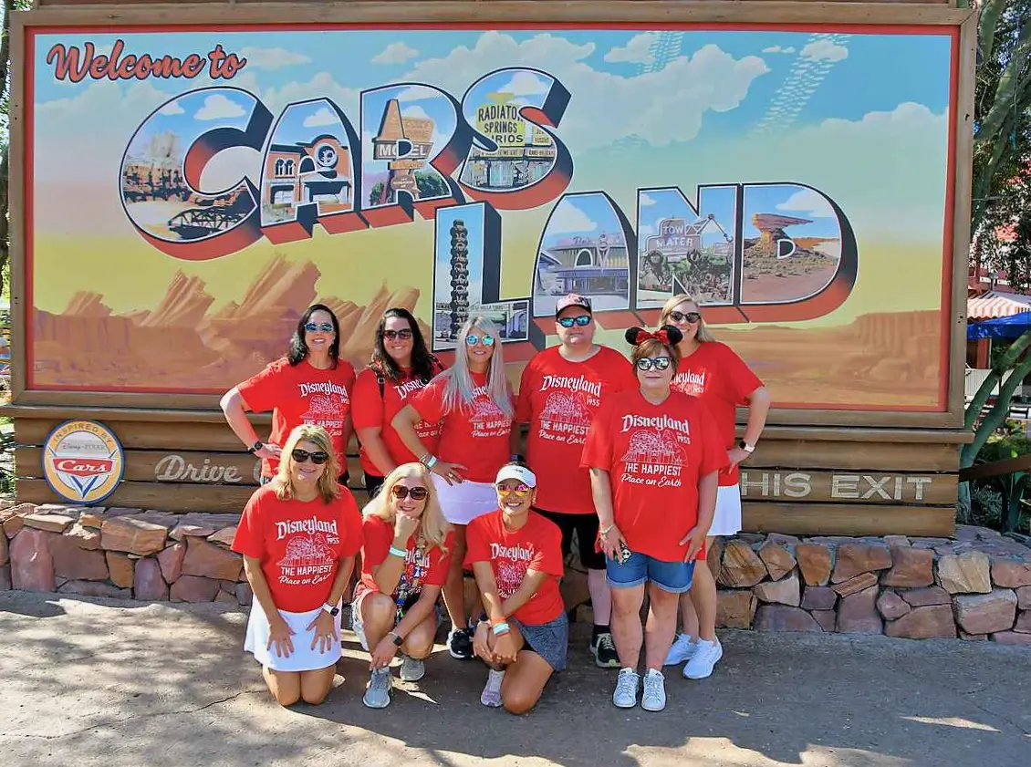 A group of people standing in front of a sign.