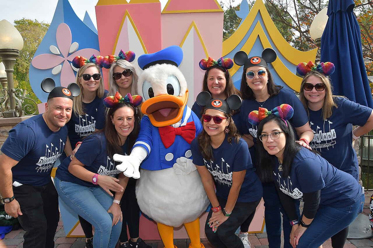 A group of people posing with donald duck.