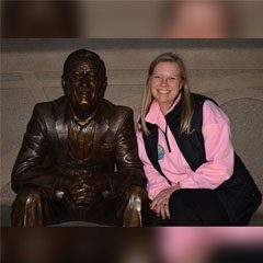 A woman sitting next to a statue of a man.