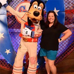 A woman posing with goofy at the disney world.