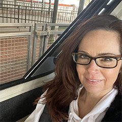 A woman with glasses sitting in the back of a bus.