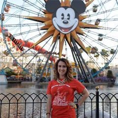 A woman standing in front of a ferris wheel.