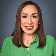 A woman in green shirt smiling for the camera.