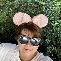 A woman with sunglasses and a pink mouse ears.