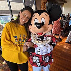 A woman standing next to mickey mouse in front of a window.