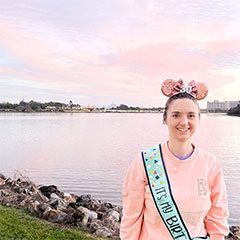 A woman in minnie mouse ears and a pink sweatshirt.